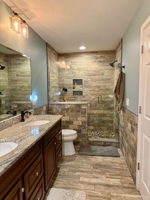 bathroom featuring an enclosed shower, vanity, wood-type flooring, tile walls, and toilet