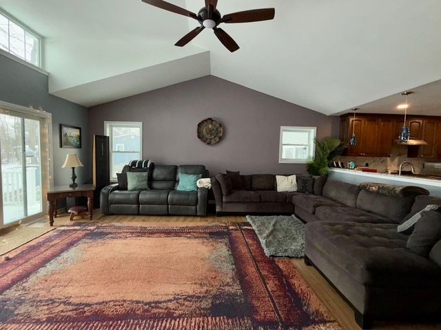 living room featuring ceiling fan, a healthy amount of sunlight, and lofted ceiling