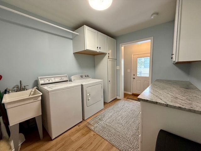 washroom featuring separate washer and dryer, light hardwood / wood-style flooring, and cabinets