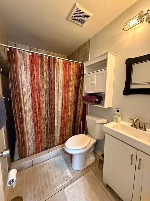 bathroom featuring a shower with shower curtain, vanity, and toilet