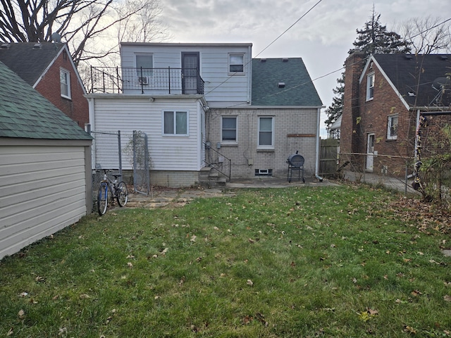 rear view of house featuring a balcony, a patio area, and a lawn