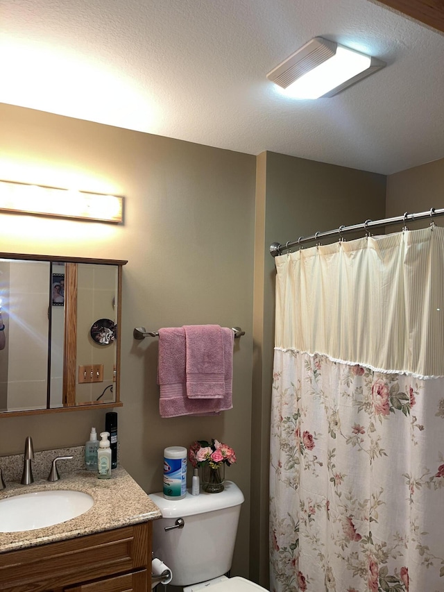 bathroom featuring a shower with shower curtain, vanity, toilet, and a textured ceiling