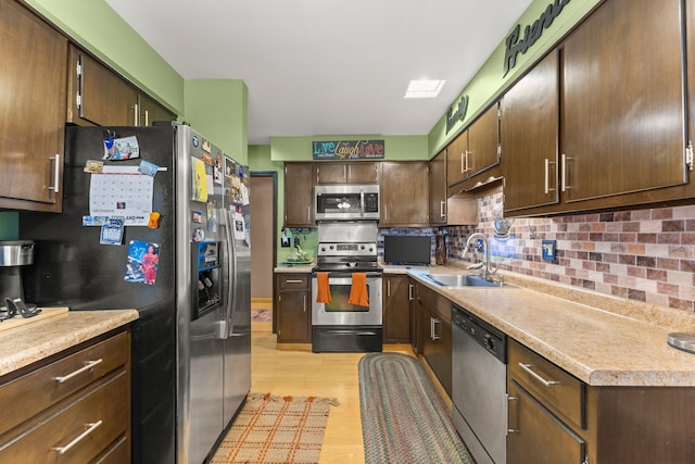 kitchen featuring sink, decorative backsplash, light wood-type flooring, dark brown cabinets, and stainless steel appliances