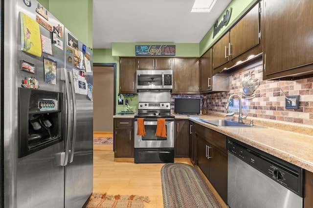 kitchen featuring sink, light wood-type flooring, tasteful backsplash, dark brown cabinets, and stainless steel appliances