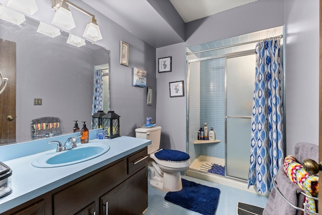 bathroom with tile patterned flooring, vanity, a shower with shower door, and toilet