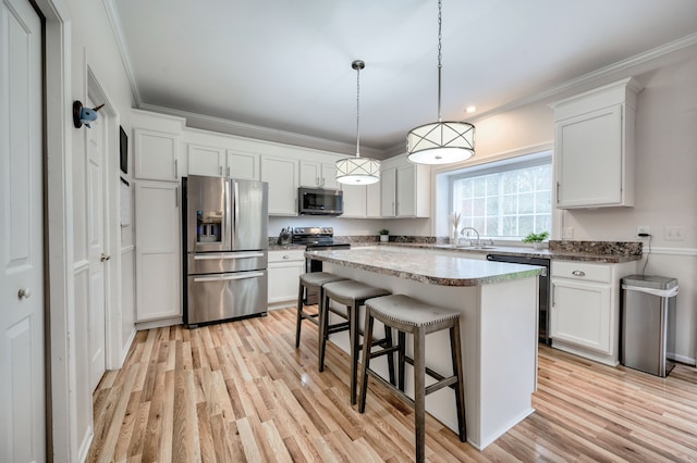 kitchen with appliances with stainless steel finishes, white cabinetry, and pendant lighting