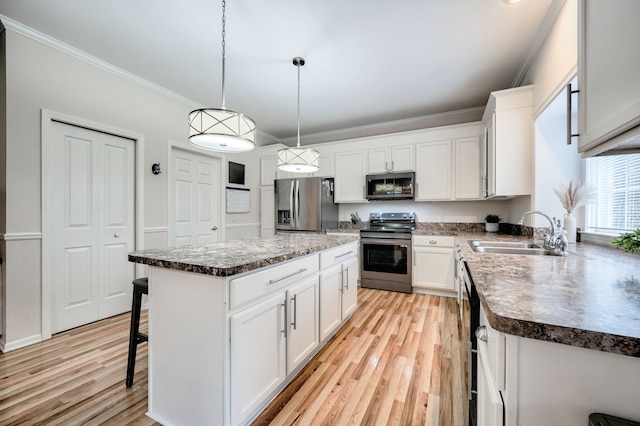 kitchen with appliances with stainless steel finishes, a breakfast bar, a kitchen island, sink, and white cabinetry