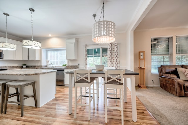 kitchen with a wealth of natural light, a kitchen breakfast bar, pendant lighting, light hardwood / wood-style floors, and white cabinets