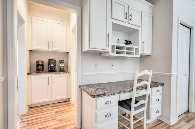 kitchen featuring white cabinets, built in desk, and light wood-type flooring