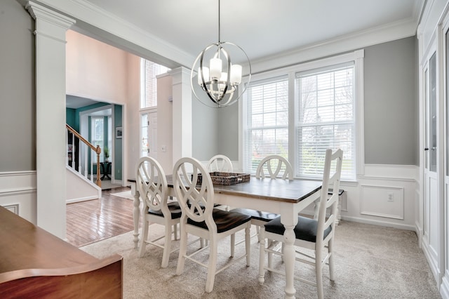 carpeted dining area with a chandelier, ornate columns, and ornamental molding