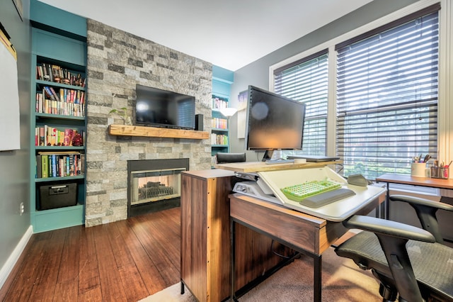 office area featuring a fireplace, dark hardwood / wood-style flooring, and built in shelves