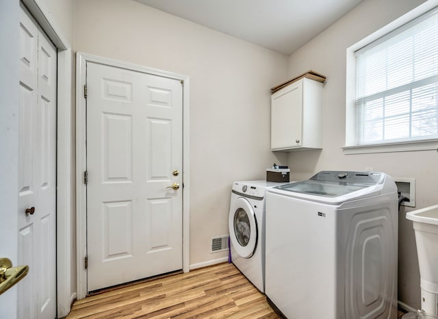 clothes washing area with light hardwood / wood-style floors, cabinets, sink, and washing machine and clothes dryer