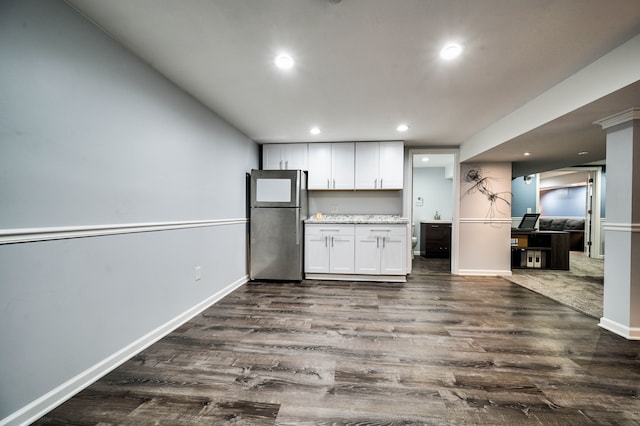 kitchen featuring white cabinets, stainless steel fridge, light stone counters, and dark wood-type flooring