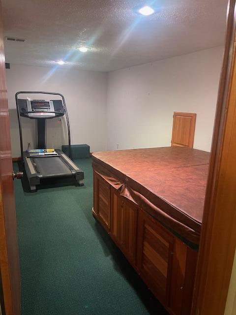 exercise room with dark colored carpet and a textured ceiling