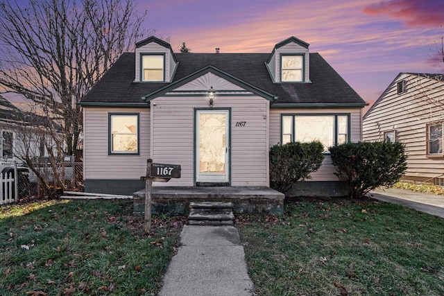 cape cod home featuring a lawn