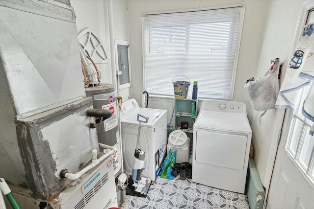 washroom featuring heating unit, washer and clothes dryer, water heater, and plenty of natural light