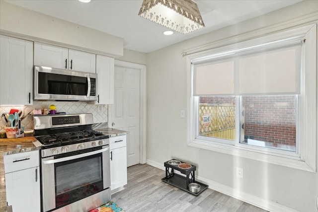 kitchen with white cabinetry, a healthy amount of sunlight, stainless steel appliances, and backsplash