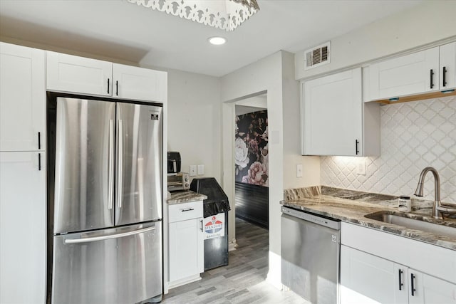 kitchen featuring tasteful backsplash, white cabinetry, sink, dark stone countertops, and stainless steel appliances