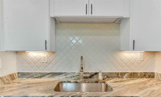 kitchen featuring white cabinetry, sink, and light stone counters