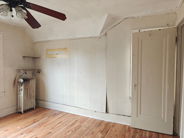 unfurnished room with ceiling fan, radiator heating unit, lofted ceiling, and light hardwood / wood-style flooring