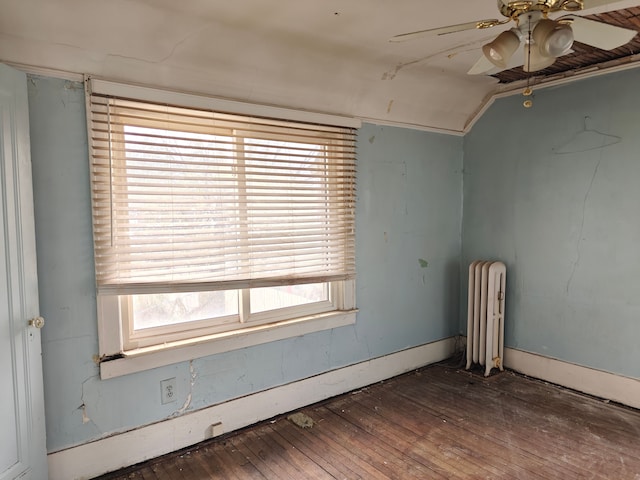 empty room with a healthy amount of sunlight, radiator heating unit, dark wood-type flooring, and vaulted ceiling