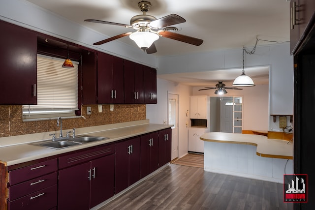 kitchen featuring backsplash, decorative light fixtures, dark wood-type flooring, and sink