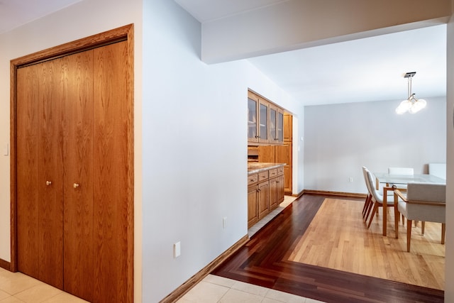 interior space featuring tile patterned floors, baseboards, and a notable chandelier