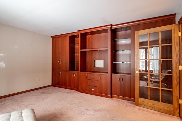 unfurnished living room featuring light carpet and baseboards