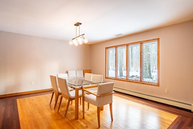 dining space with visible vents, baseboard heating, wood finished floors, a chandelier, and baseboards