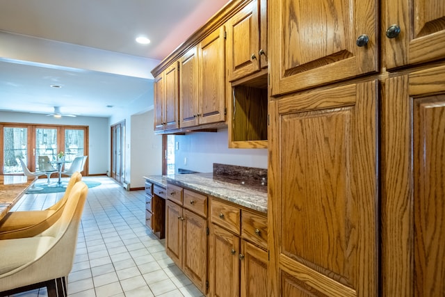 kitchen with brown cabinets, recessed lighting, a ceiling fan, light tile patterned floors, and baseboards