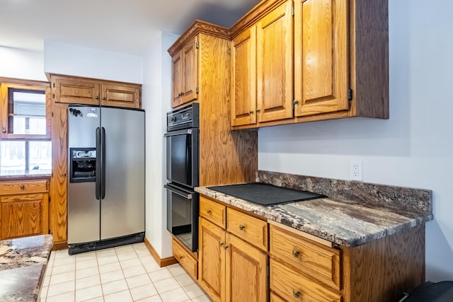 kitchen with black appliances, brown cabinetry, and light tile patterned flooring