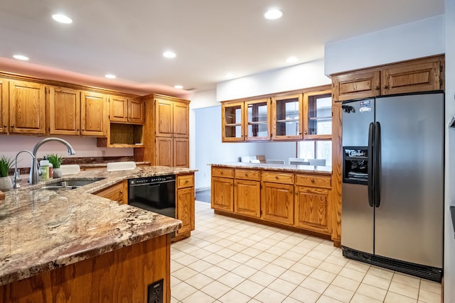 kitchen with stainless steel fridge, a sink, brown cabinetry, dishwasher, and light stone counters