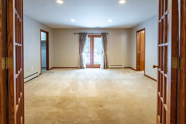 spare room featuring light carpet, baseboards, a baseboard heating unit, and french doors