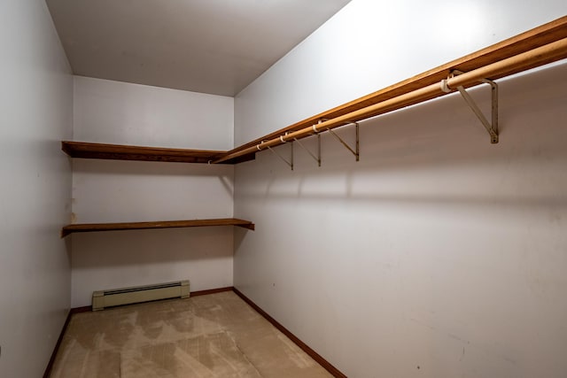 spacious closet with light colored carpet and a baseboard heating unit