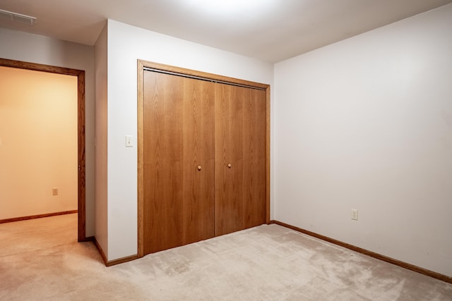 unfurnished bedroom featuring light carpet, a closet, visible vents, and baseboards