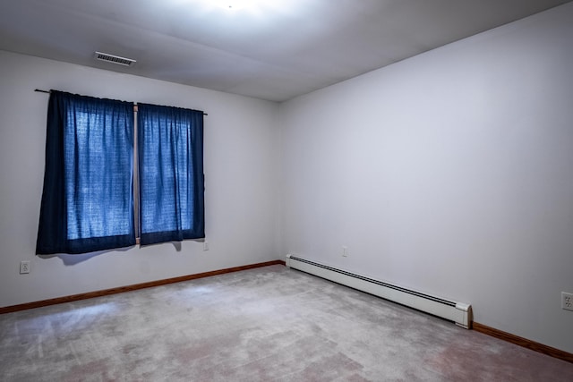 spare room featuring carpet floors, visible vents, a baseboard heating unit, and baseboards