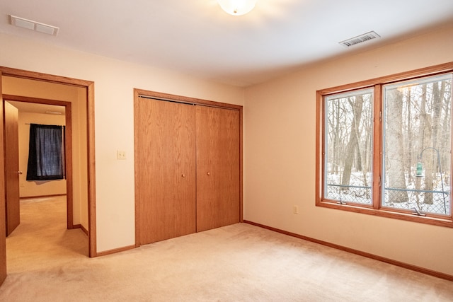 unfurnished bedroom featuring light colored carpet, a closet, visible vents, and multiple windows