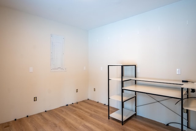 unfurnished room featuring electric panel and light hardwood / wood-style flooring