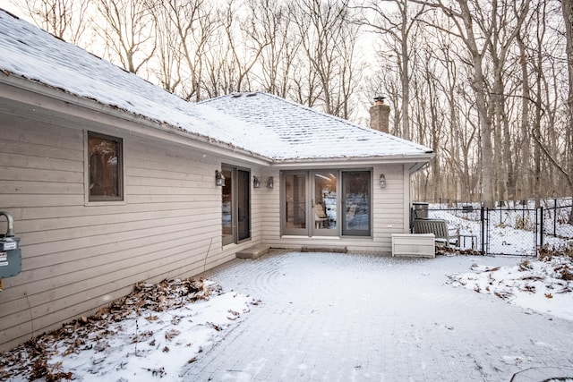 snow covered property entrance featuring fence and a chimney