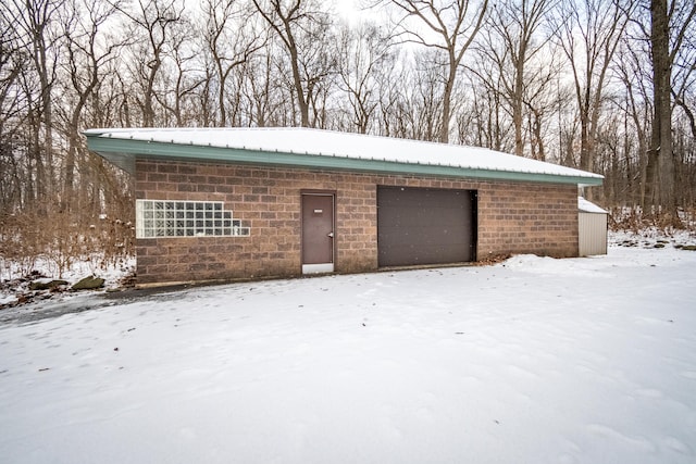 snow covered garage with a detached garage