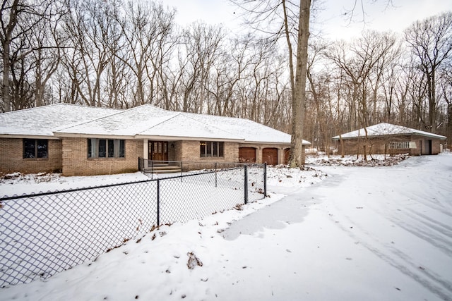 view of front of property with a garage, brick siding, and fence