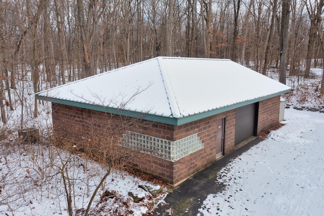 view of snow covered exterior featuring metal roof and brick siding