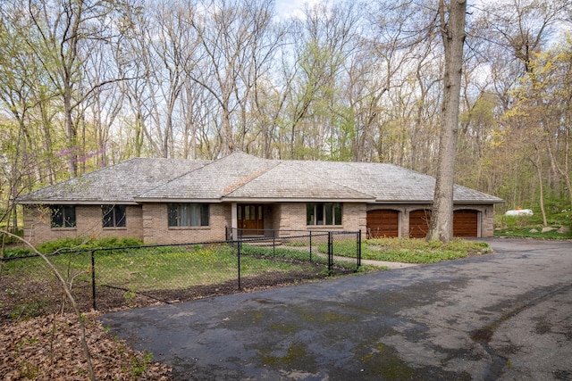 ranch-style home featuring an attached garage, brick siding, driveway, and fence