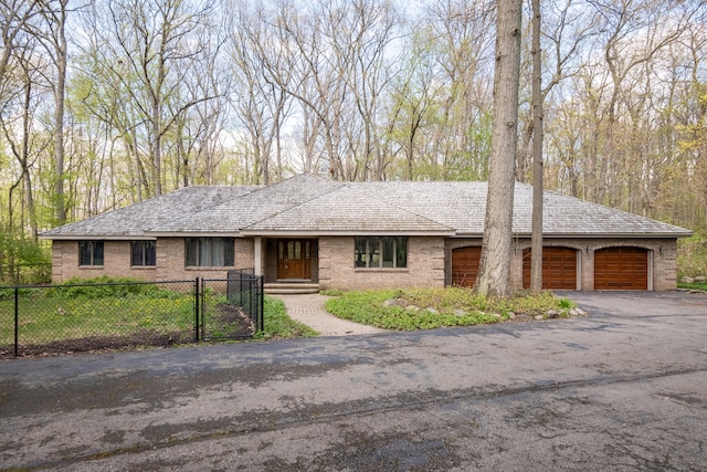 ranch-style house featuring a gate, fence, an attached garage, brick siding, and driveway