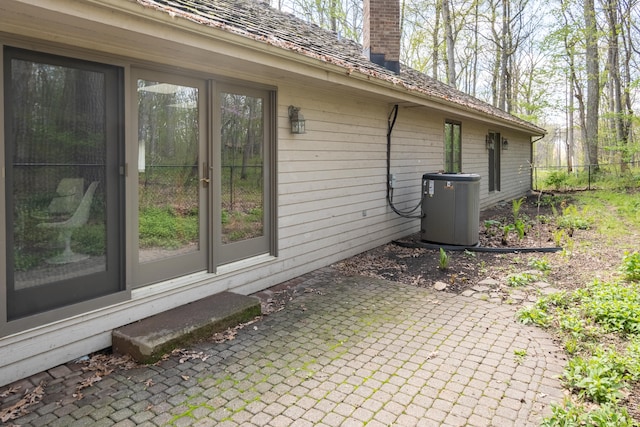 view of side of property with a patio, a chimney, and central AC unit