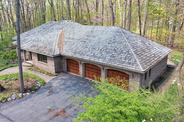 exterior space featuring driveway, brick siding, and a garage