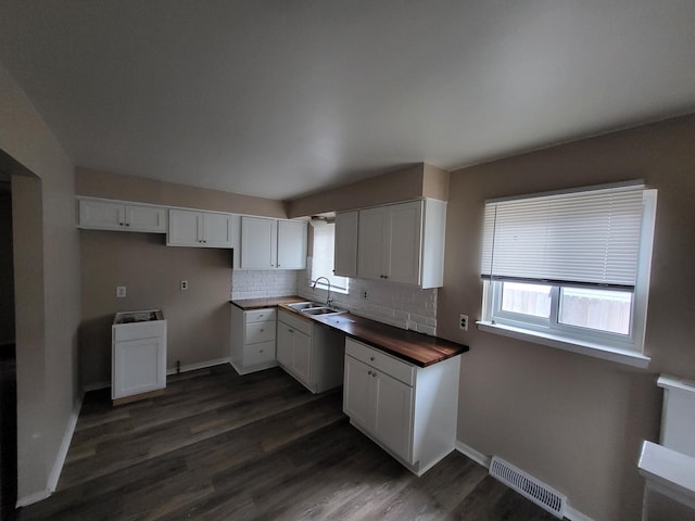 kitchen with dark wood-type flooring, sink, white cabinets, and wooden counters