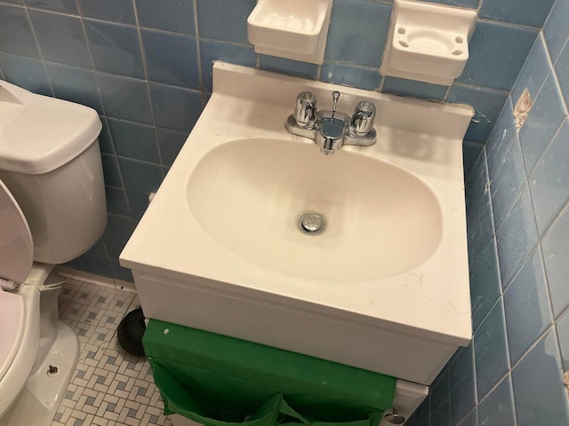 bathroom with tile patterned flooring, toilet, and tile walls