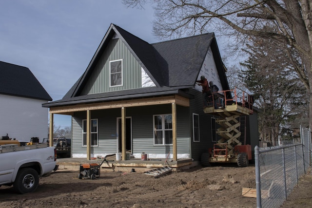 view of front of home with a porch, a shingled roof, board and batten siding, and fence