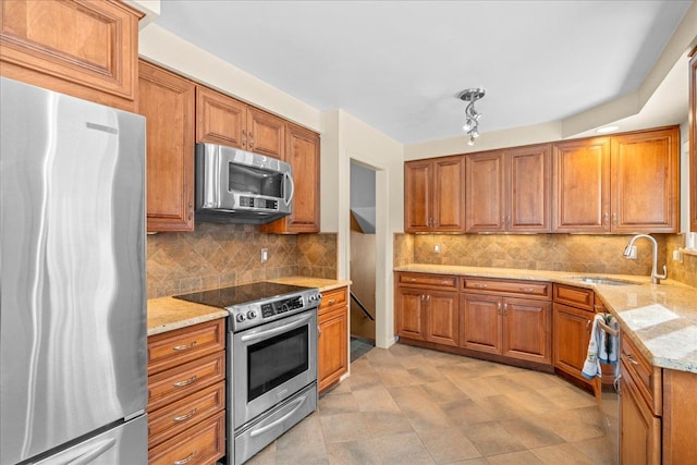 kitchen with light stone countertops, sink, backsplash, and appliances with stainless steel finishes